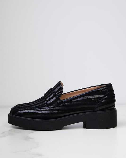 Vue de profil d'un mocassin pour femme en cuir caprin noir, révélant une silhouette élégante avec un bout amande.