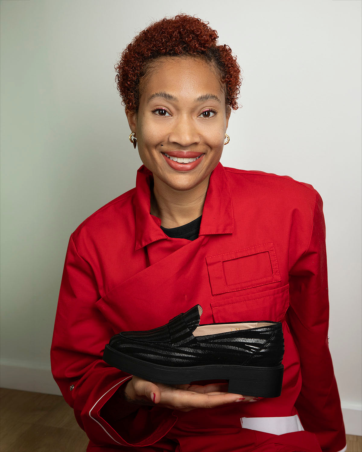 Cindy Lubin souriante, tenant le premier modèle de la marque, un mocassin pour femme à bout amande, pensé pour toutes les morphologies et fabriqué au Portugal.