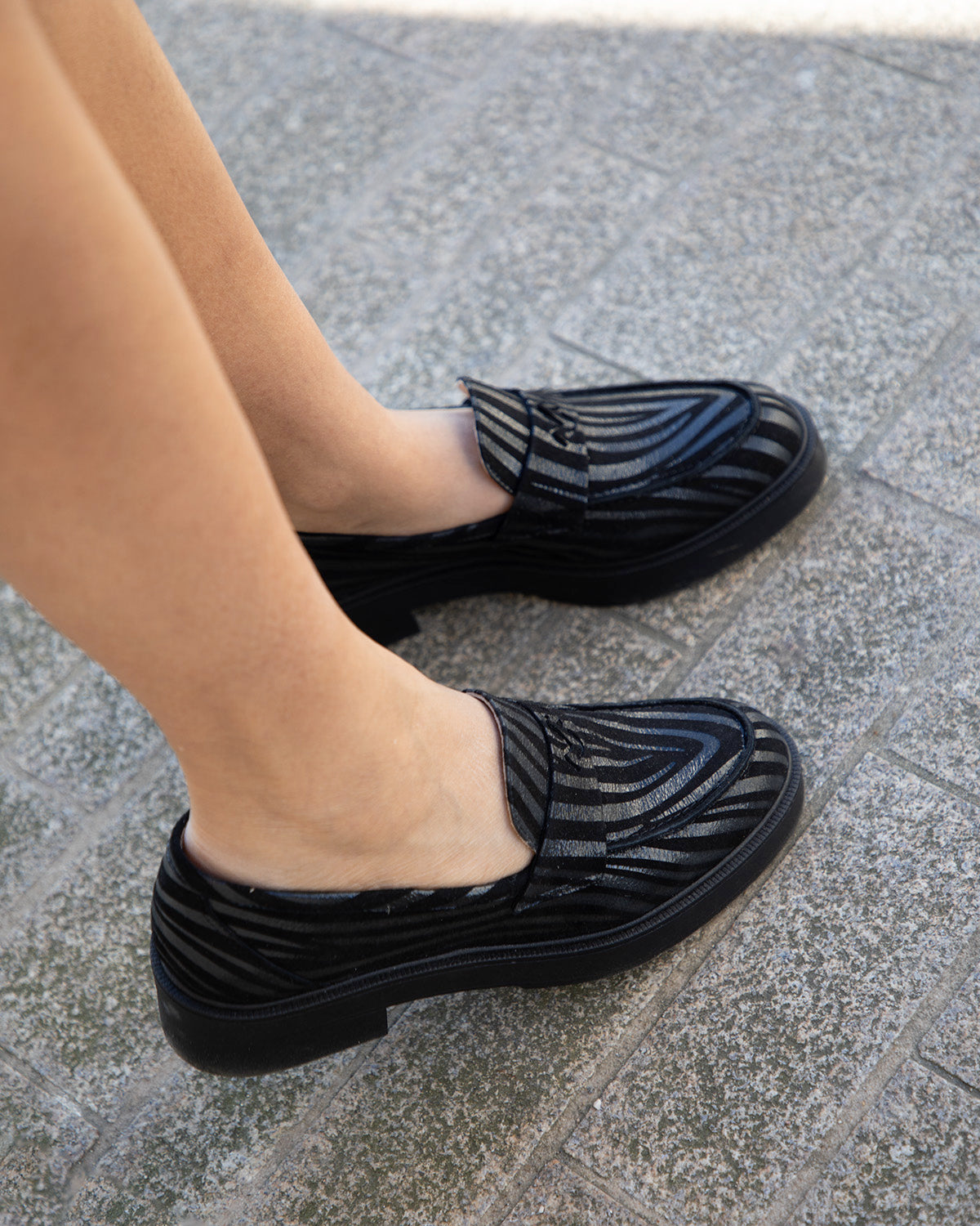 Vue plongeante de mocassins en cuir noir à bout amande portés, montrant l'élégance de la silhouette vue du dessus.