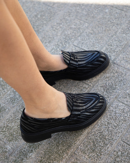 Vue plongeante de mocassins en cuir noir à bout amande portés, montrant l'élégance de la silhouette vue du dessus.