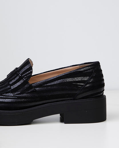 Mocassin pour femme en cuir noir à bout amande, vue de trois-quart mettant en avant la courbure élégante et la finesse du cuir caprin.